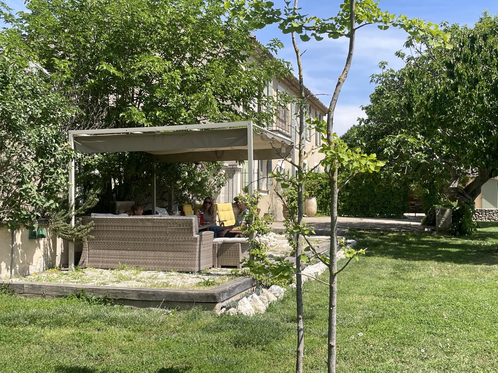Friends relaxing under a shaded pergola in a green garden in the south of France
